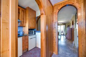 een keuken met houten kasten en een gewelfde deur bij VB Marysol - 2BR apartment close to the beach in Benalmádena