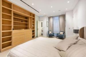 um quarto com uma cama grande e prateleiras de madeira em Stunning Mayfair 3 bed flat with terrace and fireplace em Londres
