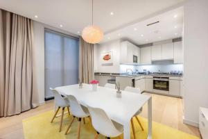 una cucina e una sala da pranzo con tavolo e sedie bianchi di Stunning Mayfair 3 bed flat with terrace and fireplace a Londra