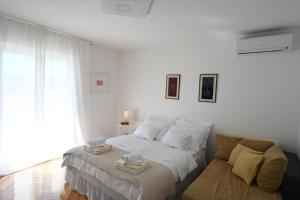 a white bedroom with a bed and a couch at NEW comfortable Apartment Vesna in Hvar
