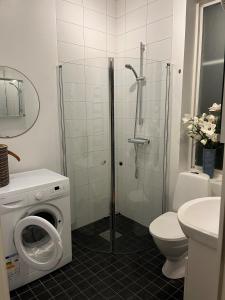y baño con ducha y lavadora. en Österport - Visby Lägenhetshotell, en Visby