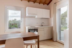 a kitchen with white cabinets and a wooden table and chairs at Podere n.8 Bio Casale Maremma in Alberese
