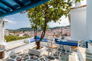 a tree on a balcony with a table and chairs at The Lemon Tree House in Skopelos Town