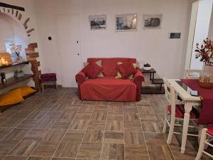 een woonkamer met een rode bank en een houten vloer bij La Casetta Dei Volontari in Pitigliano