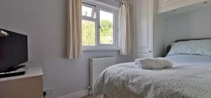 a white bedroom with a bed and a window at Chy Lowen Private rooms with kitchen, dining room and garden access close to Eden Project & beaches in Saint Blazey
