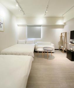 a white room with two beds and a table at 無印旅行 in Taichung