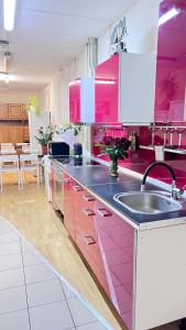 ワルシャワにあるHostel POPLAWOKのピンクのキャビネットとシンク付きのキッチンが備わります。