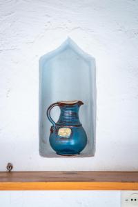 eine blaue Vase in einem Glasrahmen auf einem Regal in der Unterkunft The Lemon Tree House in Skopelos