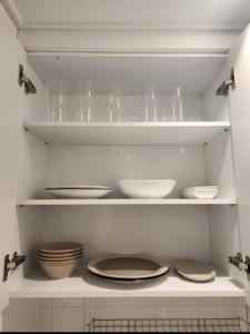 a white kitchen with bowls and plates on shelves at Koon Terrace Stay in Seoul