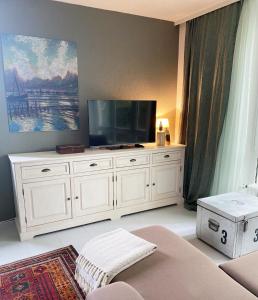 een woonkamer met een groot wit entertainmentcentrum met een flatscreen-tv bij Gästehaus am Brockeswald in Cuxhaven