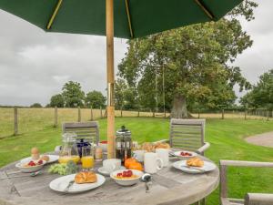 una mesa de picnic con comida con un paraguas en Bearwood House & Cottage en Pembridge