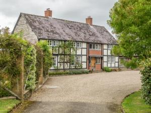 an old house with a driveway in front of it at Bearwood House & Cottage in Pembridge