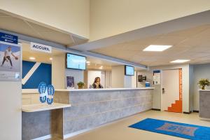a woman standing at a reception counter in a hospital lobby at ibis budget Paris Porte d'Aubervilliers in Aubervilliers