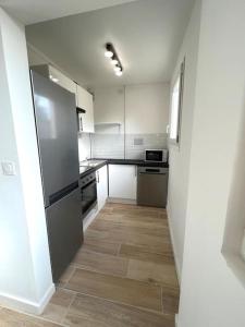 a kitchen with a refrigerator and a wooden floor at Contemporary Haven in Châtenay-Malabry