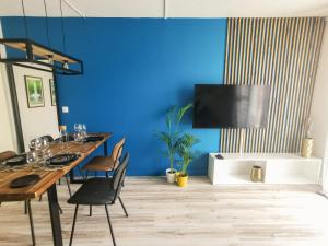 une salle à manger avec un mur bleu, une table et des chaises dans l'établissement Le Théâtre du Vieux Foyal - Appartement 4 personnes à Fort-De- France, à Fort-de-France