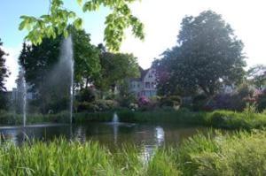 a pond with a fountain in front of a house at Villa Deichvoigt in Cuxhaven