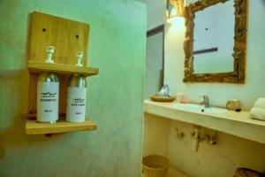 un baño con 2 botellas de odorizantes en un estante junto a un fregadero en Mvuvi Lodge, en Watamu