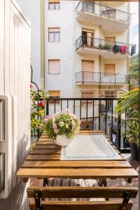 een balkon met een houten tafel en bloemen erop bij Camera privata nell'appartamento in zona residenziale con 2 piscine in Rapallo