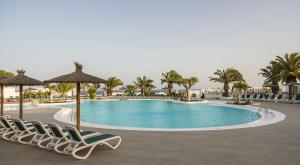 a pool at a resort with chairs and palm trees at ILUNION Costa Sal Lanzarote in Puerto del Carmen