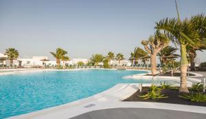 a swimming pool with palm trees in a resort at ILUNION Costa Sal Lanzarote in Puerto del Carmen