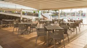 a restaurant with tables and chairs and a swimming pool at ILUNION Costa Sal Lanzarote in Puerto del Carmen