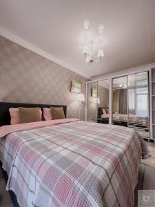 a bedroom with a large bed with a plaid blanket at RentHouse Apartments Premium Living in Chişinău