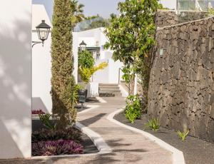 a walkway with a stone wall and a street at ILUNION Costa Sal Lanzarote in Puerto del Carmen