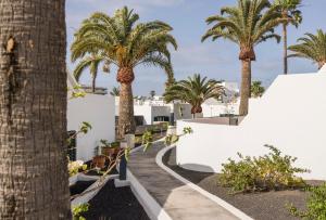 a walkway with palm trees and white buildings at ILUNION Costa Sal Lanzarote in Puerto del Carmen