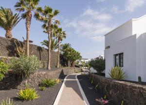 a pathway with palm trees and a white building at ILUNION Costa Sal Lanzarote in Puerto del Carmen