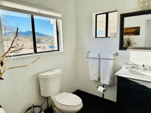 a bathroom with a toilet and a sink and a window at Ravens Nest Ranch, Fire pit , Views, Near JT Park! in Joshua Tree