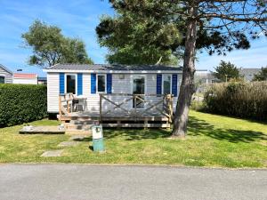 una casita azul y blanca con un árbol en Camping De Collignon, en Cherbourg-en-Cotentin