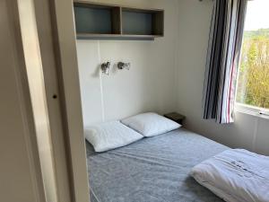 シェルブール・アン・コタンタンにあるCamping De Collignonのベッドと窓が備わる小さな客室です。