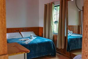 a bedroom with a bed with blue sheets and a window at Hotel da Inês in Visconde De Maua +37 photos