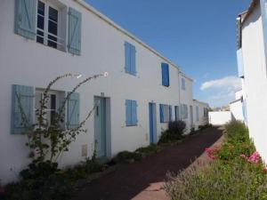 un edificio blanco con ventanas con persianas azules y una calle en Maison Saint-Gilles-Croix-de-Vie, 3 pièces, 6 personnes - FR-1-224-751, en Saint Gilles Croix de vie