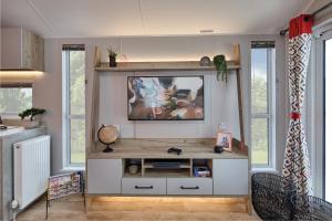 a living room with a tv on a wall with windows at Elite Holiday Caravan in Bassenthwaite