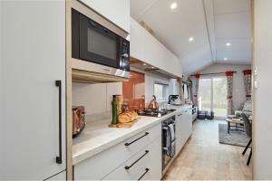 a kitchen with a stove and a microwave at Elite Holiday Caravan in Bassenthwaite