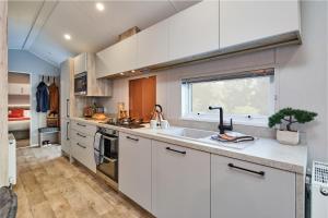 a kitchen with white cabinets and a sink and a window at Elite Holiday Caravan in Bassenthwaite