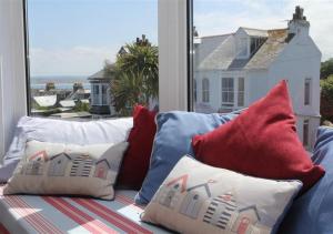 a blue couch with pillows on a balcony with a window at Atlantic Retreat 10a Ventnor Terrace in St Ives