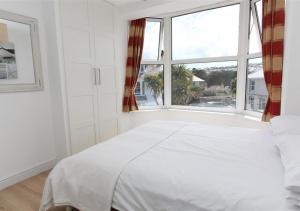 a white bedroom with a bed and a window at Atlantic Retreat 10a Ventnor Terrace in St Ives