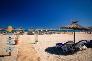 una playa de arena con sillas y sombrillas y el océano en Magnifique maison bord de mer Canet plage, en Canet-en-Roussillon