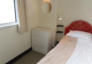 a bedroom with a red headboard and a white bed at 4 Wharf House The Wharf in St Ives