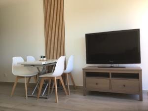 una sala da pranzo con TV e tavolo con sedie bianche di Appartement pieds dans l’eau Vue Mer Bormes Les Mimosas a Bormes-les-Mimosas
