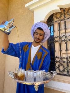 Een man met een tulband en een dienblad glazen. bij Dar Ajgal in Dourtane