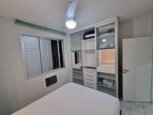um quarto com uma cama branca e uma janela em Estúdio Beira Mar em Florianópolis