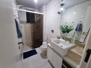 uma casa de banho branca com um lavatório e um WC em Estúdio Beira Mar em Florianópolis
