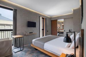 a bedroom with a large bed and a balcony at IOTA Hotel Tbilisi in Tbilisi City
