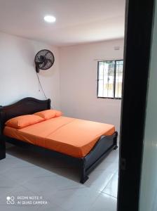 1 dormitorio con 1 cama con colcha de color naranja y ventilador en Hostal Almirante, en Ríohacha