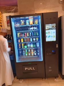 a man standing next to a soda vending machine at فندق الفخامة اوركيد 2 للغرف والشقق المفروشة in Makkah