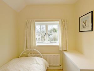 a small bedroom with a window and a chair at Church View in Earnley