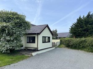 a small white house on a gravel road at Ty Efail Cottage mountain views & secure garden in Beaumaris